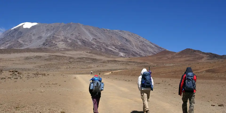 Three trekkers crossing the alpine desert toward Kibo