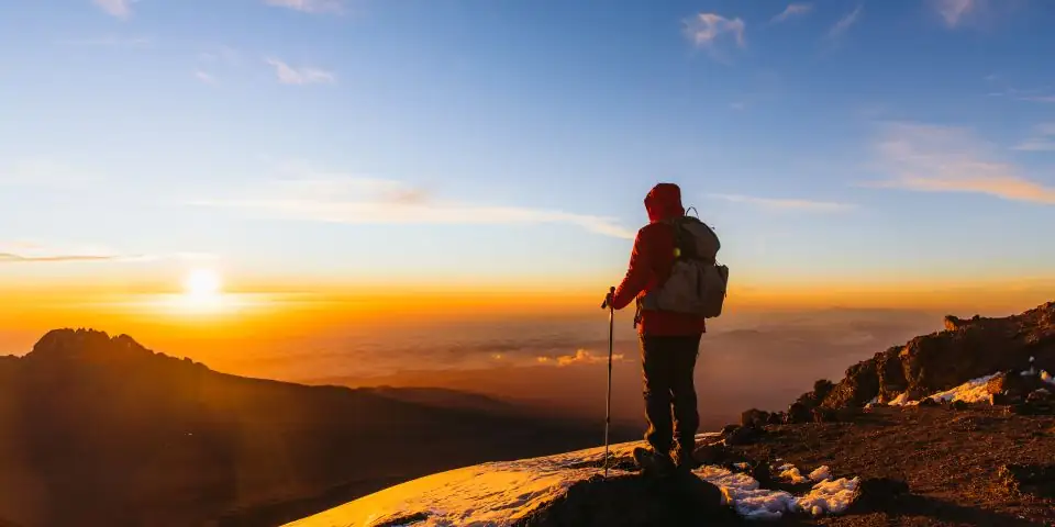 Climber silhouetted against the sunrise above the clouds