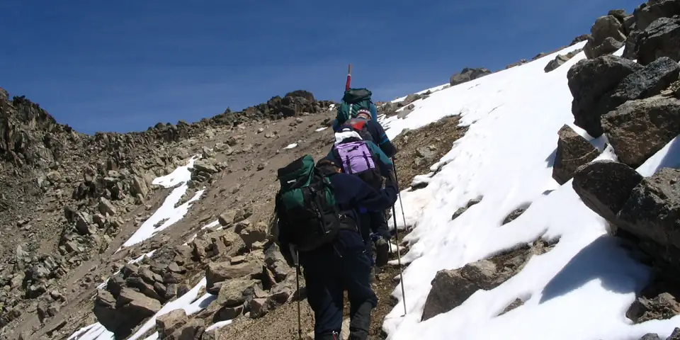 Climbers on a snowy scree slope high on the mountain
