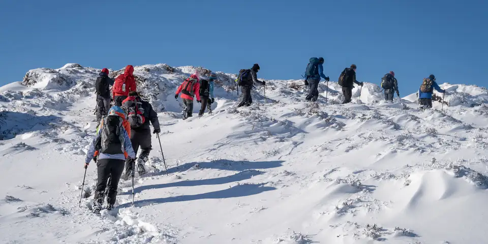 A line of climbers crossing fresh snow near the crater rim