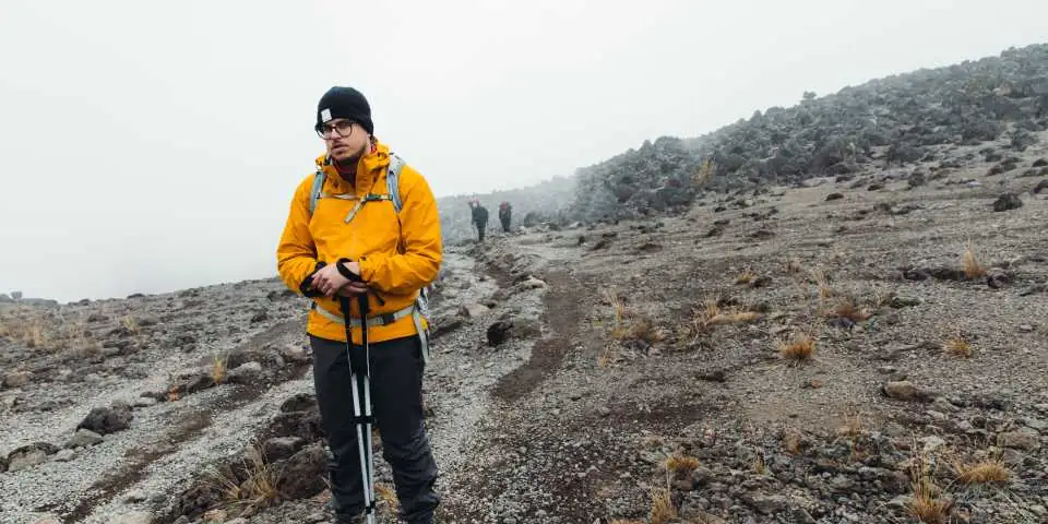 Trekker in a yellow jacket on a misty scree path